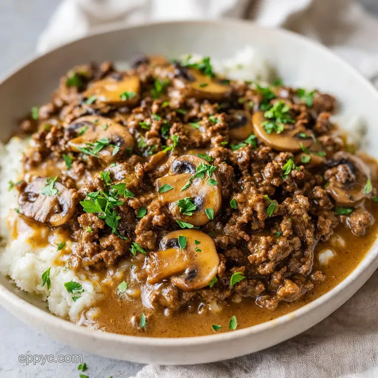 Elegant white bowl of creamy beef and sliced mushrooms, garnished with fresh parsley and wisps of steam.